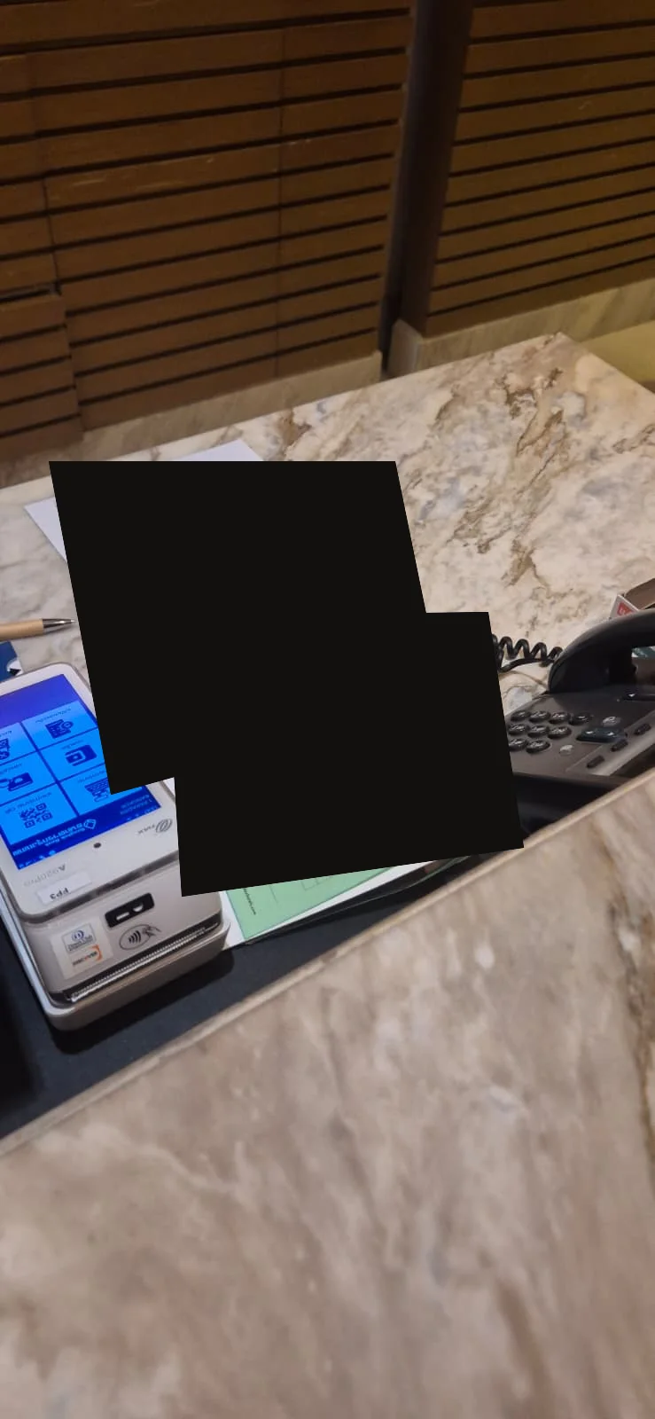 Hotel reception desk with visible paperwork permanently redacted